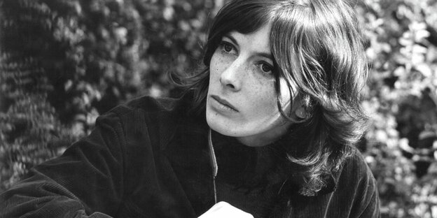 Schwarzweiß-Foto der Sängerin Bettina Wegener, sie sitz vor Blättern und schaut nach links , sie hat Sommersprossen im Gesicht