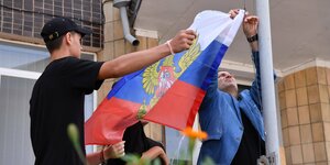 Zwei Männer hissen eine russische Flagge im besetzten Kupiansk, nahe Charkiw
