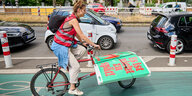 Eine Radlerin transportiert Plakate für das Volksbegehren Klimaschutz