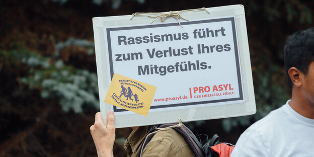 Eine Person trägt ein Schild mit der Aufschrift „Rassismus führt zum Verlust Ihres Mitgefühls“