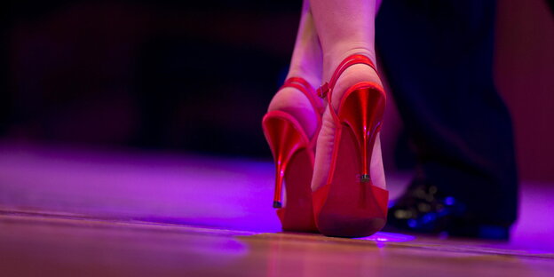 Nahaufnahme von roten High-Heels und schwarzen Männerschuhen beim Tanzen Nahaufnahme von roten High-Heels und schwarzen Männerschuhen beim Tanzen