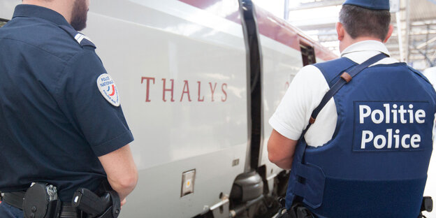 Zwei Polizisten stehen an einem Zug Zwei Polizisten stehen an einem Zug