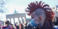 "International Womens Day" steht auf dem Kopf einer Frau, die am Internationalen Frauentag an einer Demonstration vor dem Brandenburger Tor teilnimmt. Seit genau 100 Jahren wird an jedem 8. März weltweit für Frauenrechte, für Gleichberechtigung und Emanzi
