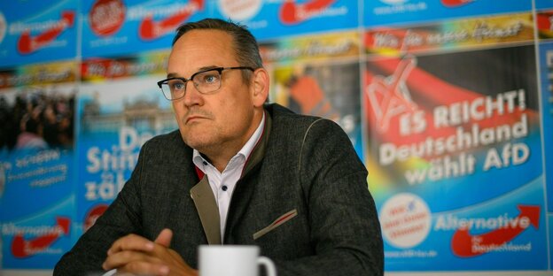Martin Reichardt sitzt vor Wahlkampf-Plakaten der AFD