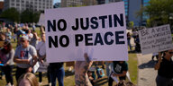 Jemand hält ein Schild hoch, auf dem "No Justin No Peace" steht