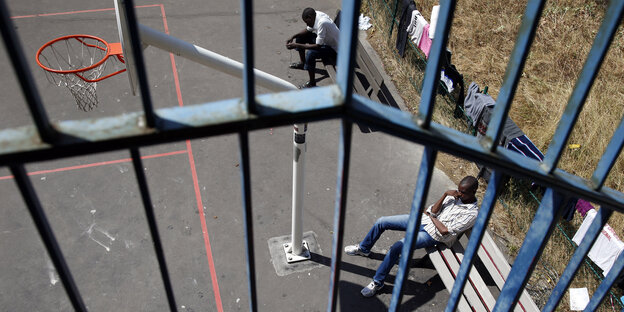 Zwei Jugendliche sitzen neben einem Basketballfeld Zwei Jugendliche sitzen neben einem Basketballfeld