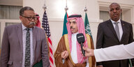Saudi Arabiens Außenminister steht vor Flaggen und spricht in ein Mikrofon.