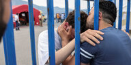 Zwei Männer umarmen sich durch ein Gitter