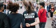 Jugendliche auf einer Straße von hinten, auf einem T-Shirt steht hinten "Halim Dener"