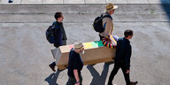 Vier Männer tragen einen Holzsarg der mit den Farben der Ampel-Regierung geschmückt ist