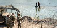 Soldaten an eine Fluss, durch den Menschen waten.