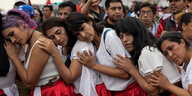 Peruanische Frauen in weißen Blusen und roten Röcken, aneinandergelehnt bei Protest in Lima gegen Präsidentin Boluarte