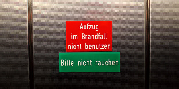 Metalltür mit Schild "Aufzug im Brandfall nicht benutzen"