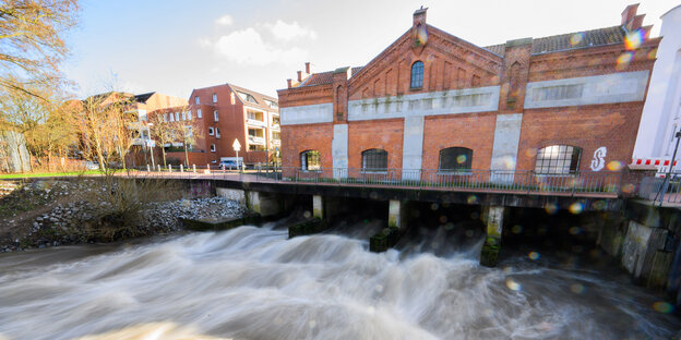 Zeigt den Fluß und ein restauriertes rotes Backsteingebäude. Reste der alten Wollwäscherei in Döhren, die einst das Viertel prägte.