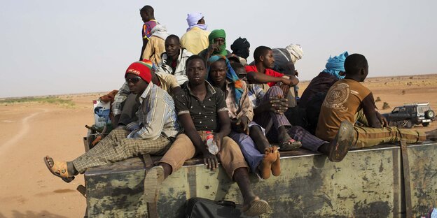 Junge Afrikaner sitzen auf einer LKW-Ladefläche Junge Afrikaner sitzen auf einer LKW-Ladefläche