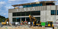 Fabrikgebäude mit „Tesla“-Schriftzug und Baustelle davor
