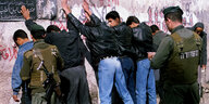 Jugendliche werden zur Kontrolle von Soldaten an die Wand gestellt.