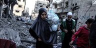Eine Frau trägt ihre Habseligkeiten durch die völlig zerstörten Straßen von Gaza-Stadt