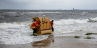 Feuerwehrleute tragen einen Strandkorb aus dem Wassser