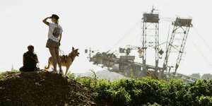 Samu und Elli stehen am Rande der Grube in Garzweiler, im Hintergrund ein Abraumbagger