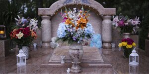 Ein Grab aus Mamor mit einer Marmorvase und Blumen