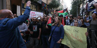 Menschen in einer engen Einkaufsstraße, sie haben Palästina-Fahnen dabei und Plakate, die "Free Palestine" fordern