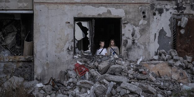 Kinder schauen aus dem fenster eines zerstörten Wohnhauses in Charkiw, Ukraine