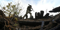 Ein ukrainischer Soldat geht mit Waffe durchs Gelände