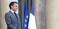 Ein lächelnder Emmanuel Macron steht vor den Flaggen von Frankreich und der EU