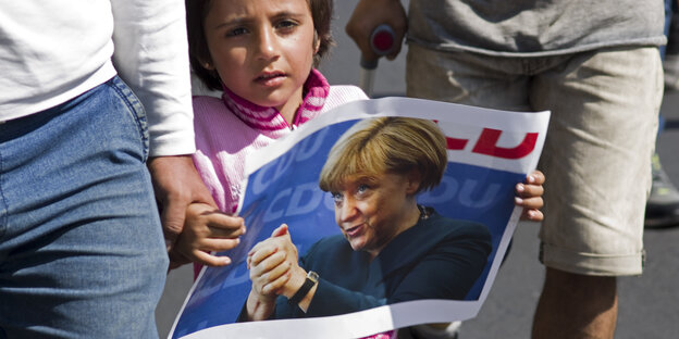 Ein Mädchen in Budapest zeigt ein Foto mit Bundeskanzlerin Merkel. Ein Mädchen in Budapest zeigt ein Foto mit Bundeskanzlerin Merkel.