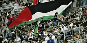 Palästinensische Fans halten eine große palästinensische Flagge im Stadion