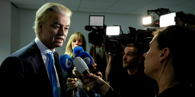Gert Wilders spricht in ein Mikrofon, umringt von Fernsehkameras