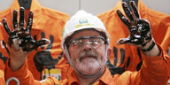 Lula da Silva mit ölverschmierten Händen in einem orangen Arbeitsanzug