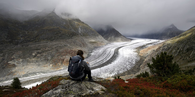Bergsteiger sitzt vor Resten eines Gletschers