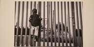 Ein Kind spielt an einem hohen Zaun, offenbar ist es gefangen