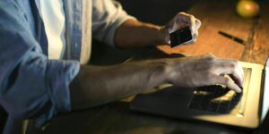 Ein Mann gibt die Infos seiner Kreditkarte für eine Online-Zahlung am Laptop an