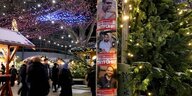 Plakate, die an die israelischen Geiseln erinnern hängen an einem Ampelmast, im Hintergrund ist ein Weihnachtsmarkt zu sehen