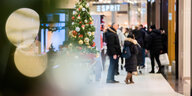 Menschen gehen am verkaufsoffenen Sonntag durch ein Einkaufszentrum am Potsdamer Platz in Berlin, sie sind nur schemenhaft zu erkennen