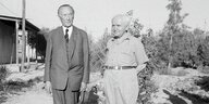 Adenauer und Ben Gurion stehen in der Negev Wüste nebeneinander, die Schatten der Fotografen liegen auf dem Boden vor ihnen