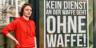 Die Klägerin Frida Henkel neben ihrem verfremdeten Plakat, einem Bundeswehrwerbeplakat mit der Aufschrift: Kein Dienst an der Waffe geht ohne Waffe!