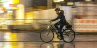 Eine Fahrradfahrerin in der Stadt bei Schneegestöber