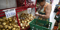 Frau mit Einkaufskorb vor Regal mit Kartoffeln