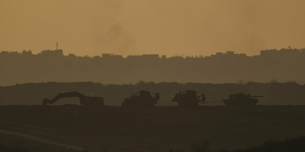 Ein israelischer Panzer und mehrere Bulldozer fahren im Gazastreifen, vom Süden Israels aus gesehen.