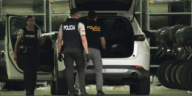 Polizisten stehen um ein Auto mit offener Heckklappe herum