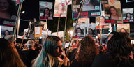 Demoszene in Tel Aviv am Abend. Junge Frauen halten Schilder mit Bildern von Verschleppten hoch