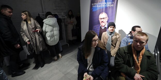 Menschen im Kampagnenbüro von Nadeschdin, an der Wand hängt ein Plakat mit dem Konterfei des Kandidaten