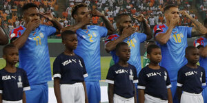 Vier Spieler der DR Kongo halten sich, während die Hymne gespielt wird, eine Hand vor den Mund und zeigen mit zwei Fingern der anderen Hand auf ihrer Schläfen