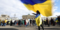 Eine Frau schwingt die ukrainische Flagge vor dem Brandenburger Tor