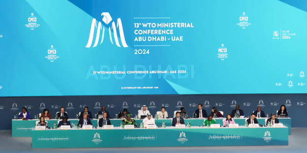 Ein Foto der WTO-Konferenz in Abu-Dhabi. Man sieht Menschen auf einem Podium sitzen.