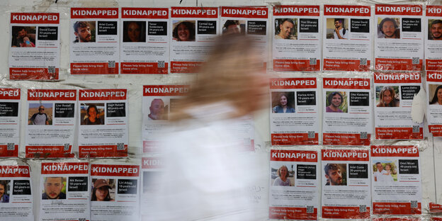 Eine Frau läuft an Postern der Gekidnappten vorbei